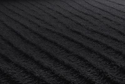 The primary subject of the image is a black and white patterned fabric. The setting is a black background, and the visual style is a close-up of the fabric. The colors and mood of the image are predominantly black and white, giving it a classic and timeless appearance.