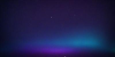 The primary subject of the image is the night sky, which is filled with stars. The setting is a dark, star-filled sky, and the visual style is a photo. The colors and mood of the image are predominantly dark and serene, with the stars providing a sense of depth and beauty.