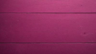 The primary subject of the image is a pink wall. The setting is a room with a wooden wall, and the visual style is a photo. The dominant colors are pink, and the overall atmosphere is warm and inviting.