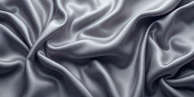 The primary subject of the image is a close-up of a piece of fabric, likely a silk material. The setting is a room with a backdrop of a wall, and the visual style appears to be a photo. The colors in the image are predominantly grays and silvers, creating a calm and sophisticated atmosphere.