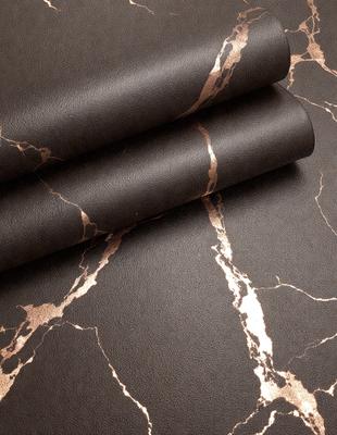 The primary subject of the image is a piece of leather, which is the main object in the scene. The leather is displayed on a marble surface, creating a visually appealing contrast between the natural texture of the leather and the smooth, polished appearance of the marble. The visual style of the image is a close-up of the leather, showcasing its details and texture. The colors in the image are predominantly brown and black, giving the scene a sophisticated and elegant atmosphere.