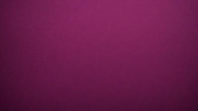 The primary subject of the image is a large, purple wall. The setting is a room with a pink background. The visual style is a close-up of the wall, which gives a sense of depth and texture. The dominant colors are purple and pink, creating a warm and inviting atmosphere.