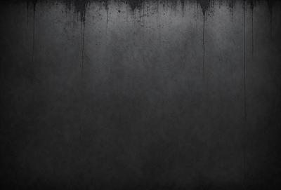 The primary subject of the image is a gray wall with a textured surface. The setting is a room with a gray background. The visual style is a black and white photo. The dominant colors are gray, and the overall atmosphere is moody and dramatic.