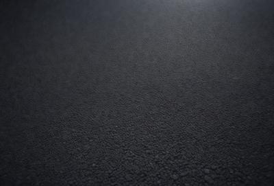 The primary subject of the image is a black surface, which appears to be a blacktop or a dark grey floor. The setting is a room with a black background, and the visual style is a close-up of the black surface. The colors and mood of the image are predominantly dark and moody, with the black surface being the main focus.