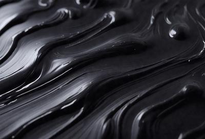 The primary subject of the image is a close-up of a black, swirling, and flowing substance, which appears to be a liquid or a viscous material. The setting is a dark background, which contrasts with the flowing substance. The visual style of the image is a close-up, which emphasizes the swirling and flowing nature of the substance. The colors and mood of the image are predominantly dark and moody, with the black substance creating a dramatic and intense atmosphere.