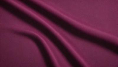 The primary subject of the image is a purple fabric, which is the main object, scene, or focus of the image. The setting or background is a dark background, which contrasts with the purple fabric. The visual style of the image is a close-up of the purple fabric, showcasing its texture and pattern. The colors and mood of the image are predominantly purple, creating a calm and serene atmosphere.
