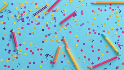 The primary subject of the image is a close-up of a pencil with a yellow and purple eraser. The setting is a blue table, and the visual style appears to be a photo. The colors and mood of the image are vibrant and lively, with the blue table and the yellow and purple pencil creating a cheerful atmosphere.