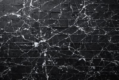 The primary subject of the image is a brick wall with a black background. The setting is a brick wall, and the visual style is a photo. The dominant colors are black and white, creating a moody atmosphere.