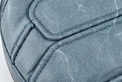 The primary subject of the image is a blue leather item, possibly a purse or a bag. The setting is a close-up of the item, showcasing its texture and details. The visual style is a realistic representation of the leather item, with no indication of digital art or illustration. The colors and mood of the image are predominantly blue, giving it a calm and serene atmosphere.