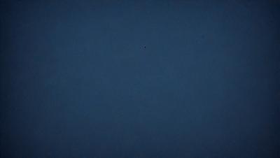 The primary subject of the image is the night sky, which is a dark blue color. The setting is a vast, open space with no visible landmarks or objects. The visual style is a natural, unaltered photograph of the night sky. The colors and mood convey a sense of tranquility and peacefulness, as the sky is void of any distractions or light sources.