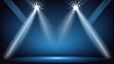 The primary subject of the image is a stage with a blue background. The stage is illuminated by two bright spotlights, creating a dramatic and theatrical atmosphere. The setting is a stage, and the visual style is a photo. The colors and mood of the image are predominantly blue, giving it a calm and serene appearance.