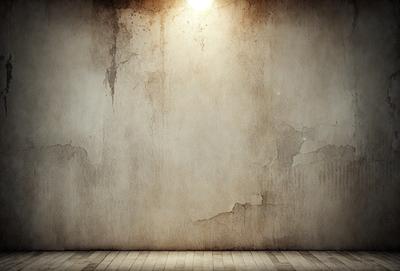 The primary subject of the image is a large, dirty, and peeling wall. The setting is a room with a wooden floor. The visual style is a photo, and the colors and mood are dark and dingy.