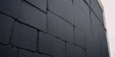 The primary subject of the image is a brick wall. The setting is a dark room, and the visual style is a photo. The dominant colors are black and grey, creating a moody atmosphere.