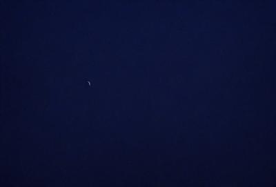 The primary subject of the image is the moon, which is visible in the night sky. The setting is a dark, starry night with a clear view of the moon. The visual style is a photo of the moon and the night sky. The colors and mood of the image are predominantly dark and serene, with the moon being the main focal point.