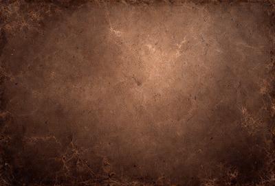 The primary subject of the image is a brown, textured surface, which appears to be a piece of leather or a similar material. The setting is a close-up of the surface, with no background or additional elements visible. The visual style is a close-up of the material, showcasing its texture and details. The colors and mood of the image are predominantly brown and earthy, giving it a natural and rustic feel.