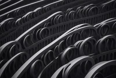 The primary subject of the image is a large number of black metal rings or circles arranged in a pattern. The setting appears to be a dark room, and the visual style is a close-up of the rings. The dominant colors are black, and the overall atmosphere is mysterious and intriguing.