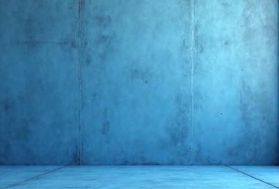 The primary subject of the image is a blue wall with a cement texture. The setting is a room with a blue wall, and the visual style is a photo. The dominant colors are blue and grey, creating a calm and serene atmosphere.