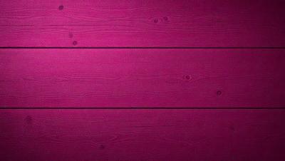 The primary subject of the image is a pink wall with a wooden texture. The setting is a room with a wooden wall, and the visual style is a close-up of the wall. The dominant colors are pink and brown, creating a warm and inviting atmosphere.