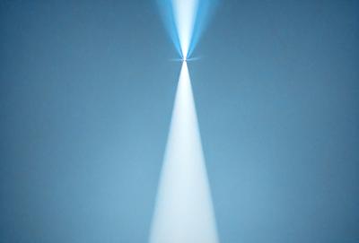 The primary subject of the image is a bright light, which appears to be a spotlight or a light source. The light is shining downwards, creating a beam of light. The setting is a dark blue background, which contrasts with the bright light. The visual style of the image is a close-up of the light source, emphasizing its intensity and creating a dramatic effect. The colors and mood of the image are predominantly dark and moody, with the bright light serving as a focal point and a source of contrast.