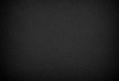 The primary subject of the image is a black background. The setting is a dark, empty space with no visible objects or details. The visual style is a black and white photo, which gives the image a classic and timeless appearance. The colors and mood are predominantly dark and moody, creating a sense of mystery and depth.
