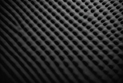 The primary subject of the image is a close-up of a black and white patterned surface, which appears to be a textured material. The setting is a dark background, which contrasts with the patterned surface. The visual style is a combination of a photo and a digital art, illustration, or drawing. The dominant colors are black and white, creating a classic and timeless atmosphere.