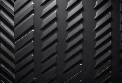 The primary subject of the image is a close-up of a black tire with a pattern of white and black stripes. The setting is a black background, which emphasizes the tire's design. The visual style is a photo, capturing the details of the tire's pattern. The colors and mood of the image are predominantly black and white, giving it a classic and timeless appearance.