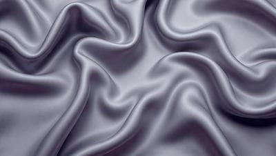 The primary subject of the image is a close-up of a piece of fabric, which appears to be a silk material. The setting is a room with a gray background, and the visual style is a detailed, close-up view of the fabric. The colors and mood of the image are predominantly gray, giving it a calm and sophisticated atmosphere.