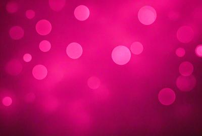 The primary subject of the image is a pink background with a pattern of pink dots. The setting is a dark background, which contrasts with the pink dots. The visual style is a close-up of the pink dots, creating a visually striking and vibrant scene. The colors and mood of the image are predominantly pink, giving it a warm and inviting atmosphere.