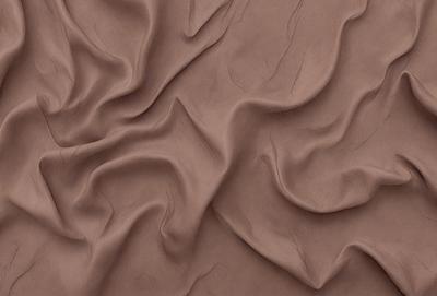 The primary subject of the image is a piece of brown fabric, possibly a piece of leather or a piece of cloth. The setting is a close-up view of the fabric, showcasing its texture and details. The visual style is a close-up, focusing on the fabric's texture and appearance. The colors and mood of the image are predominantly brown, giving it a warm and natural feel.