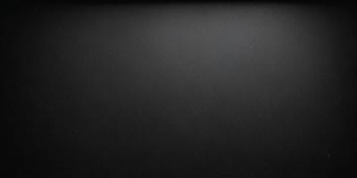 The primary subject of the image is a black background with a white dot in the upper right corner. The setting is a dark room, and the visual style is a black and white photo. The colors and mood of the image are predominantly dark and moody, with the white dot being the only bright spot in the scene.