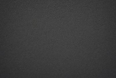 The primary subject of the image is a black surface, which appears to be a wall or a piece of fabric. The setting is a dark room, and the visual style is a close-up of the black surface. The colors and mood of the image are predominantly dark and moody, with the black surface being the main focus.