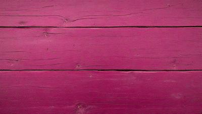 The primary subject of the image is a wooden wall with a pink color. The setting is a room with a wooden surface, and the visual style is a close-up of the wall. The dominant colors are pink and brown, creating a warm and inviting atmosphere.