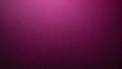 The primary subject of the image is a large, pink wall. The setting is a dark room, and the visual style appears to be a photo. The dominant colors are pink and purple, creating a warm and inviting atmosphere.
