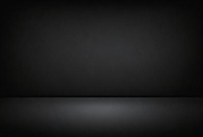 The primary subject of the image is a black wall. The setting is a dark room, and the visual style is a black and white photo. The colors and mood of the image are predominantly dark and moody, with the black wall serving as the focal point.