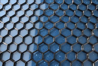 The primary subject of the image is a blue and black patterned surface, which appears to be a wall or a window. The setting is indoors, with the patterned surface being the main focus of the image. The visual style is a close-up of the pattern, showcasing the intricate details of the design. The colors and mood of the image are predominantly blue and black, creating a sense of depth and sophistication.