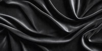 The primary subject of the image is a black fabric, which appears to be a piece of silk. The setting is a black background, which highlights the fabric's texture and color. The visual style is a close-up of the fabric, showcasing its intricate details. The colors and mood of the image are predominantly dark, with the black fabric serving as the focal point.
