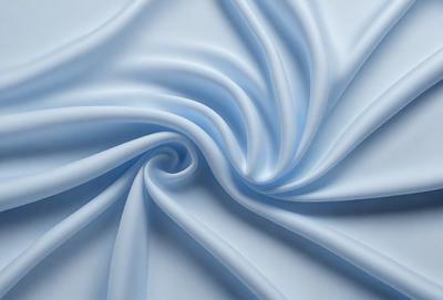 The primary subject of the image is a blue fabric, which appears to be a piece of cloth or a sheet. The setting is a white background, which provides a clean and uncluttered appearance. The visual style is a close-up of the fabric, showcasing its texture and details. The colors and mood of the image are predominantly blue, creating a calm and soothing atmosphere.