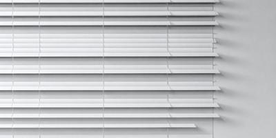 The primary subject of the image is a white shade or blind, which is covering a window. The setting is indoors, with the window being the main focus of the image. The visual style is a close-up of the shade, showcasing its details. The colors in the image are predominantly white, giving the scene a clean and minimalist appearance.