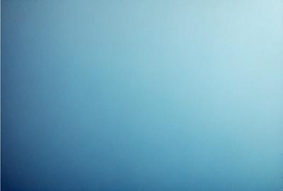 The primary subject of the image is a large, empty blue sky. The setting is a vast, open space with no visible landmarks or objects. The visual style is a natural, untouched landscape. The colors and mood are predominantly blue, creating a serene and peaceful atmosphere.