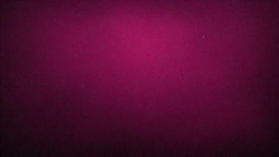 The primary subject of the image is a large, pink wall. The setting is a dark room, and the visual style appears to be a photo. The dominant colors are pink and purple, creating a warm and inviting atmosphere.