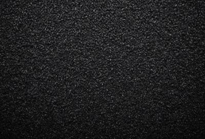 The primary subject of the image is a black carpet with a pattern of small black circles. The setting is a black background, which creates a striking contrast with the carpet. The visual style is a close-up of the carpet, showcasing its texture and pattern. The colors and mood of the image are predominantly black, giving it a sleek and modern appearance.