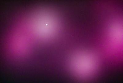 The primary subject of the image is a bright star in the sky. The setting is a purple background, which creates a contrasting and visually striking scene. The visual style is a photo, capturing the star and its surroundings. The colors and mood of the image are predominantly purple, giving it a unique and artistic appearance.