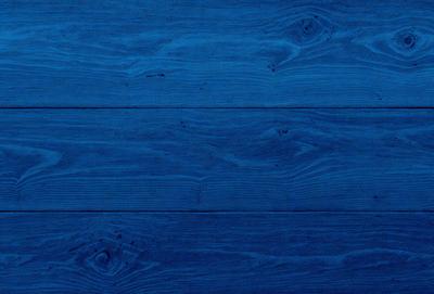 The primary subject of the image is a wooden floor with a blue tint. The setting is a room with a blue wooden floor, and the visual style is a close-up of the wooden floor. The colors and mood of the image are predominantly blue, creating a calm and serene atmosphere.