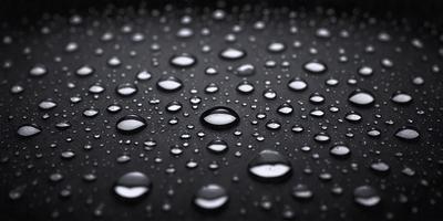 The primary subject of the image is a close-up of a rainy surface, likely a black background, with water droplets forming a pattern. The setting is a dark background, and the visual style appears to be a photo or a close-up of a rainy surface. The colors and mood of the image are predominantly dark, with the water droplets creating a moist and atmospheric scene.