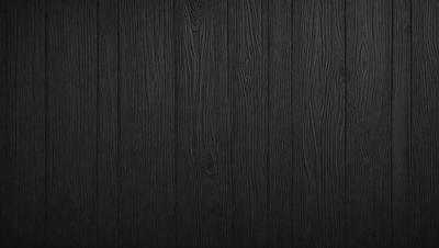 The primary subject of the image is a wooden wall. The setting is a dark room, and the visual style is a close-up of the wooden wall. The colors and mood of the image are predominantly dark, with the wooden wall being the main focus.