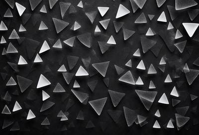 The primary subject of the image is a pattern of triangles, which are arranged in a black background. The setting appears to be a black surface, possibly a wall or a piece of artwork. The visual style of the image is a combination of digital art and illustration, as the triangles are created using a digital medium. The dominant colors in the image are black and white, giving it a clean and modern appearance. The overall atmosphere of the image is minimalistic and geometric.