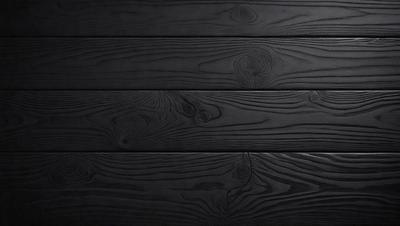 The primary subject of the image is a wooden wall with a black background. The setting is a room with a wooden floor. The visual style is a close-up of the wooden wall, showcasing its texture and details. The colors and mood of the image are dark and moody, with the black wooden wall and floor creating a dramatic atmosphere.