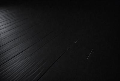 The primary subject of the image is a black background with a pattern of white lines. The setting is a dark room, and the visual style appears to be a digital art or illustration. The dominant colors are black and white, creating a moody and dramatic atmosphere.
