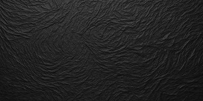 The primary subject of the image is a black background with a pattern of wrinkles and folds. The setting is a dark room, and the visual style is a close-up of the black background. The colors and mood of the image are predominantly dark and moody, with the black background creating a dramatic and intense atmosphere.