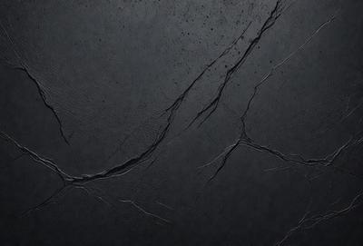 The primary subject of the image is a black surface with visible cracks and crevices. The setting is a dark room, and the visual style appears to be a close-up of the black surface. The colors and mood of the image are predominantly dark and moody, with the black surface and cracks creating a sense of depth and texture.